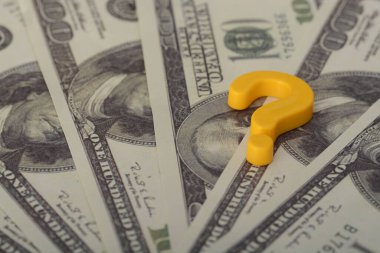 Finansal belirsizliğin ortasında, soru işareti paralarının üzerinde asılı, mali geleceklerinin belirsizliğini temsil ediyor ve bir cevap arayışına yol açıyor.