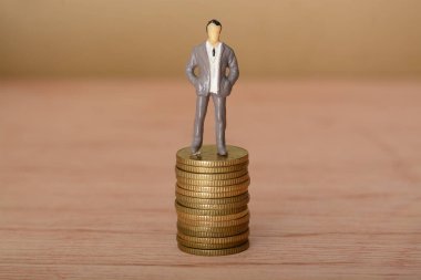 Girişimci işadamı, bozuk para yığınının üzerinde duruyor, sarsılmaz bir kararlılıkla ileriye bakıyor, başarmak için yeni fırsatlar yakalamaya hazır..