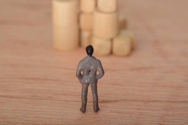 Düşüncelere dalmış ve etrafı tahta bloklarla çevrili olan işadamı, sorun ve gelişim mücadelesi üzerine kafa yorarak şirket için bir çözüm aradı.