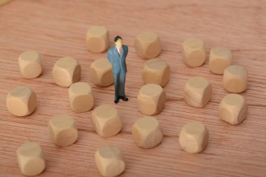 Düşüncelere dalmış ve etrafı tahta bloklarla çevrili olan işadamı, sorun ve gelişim mücadelesi üzerine kafa yorarak şirket için bir çözüm aradı.