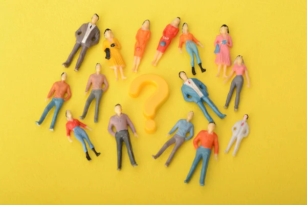 The question mark symbol, isolated on a yellow background, draws the attention of a diverse group of people, inviting them to join in on an exploration of knowledge and curiosity