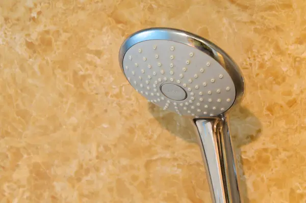 A close-up of a shower head in a modern bathroom, showcasing sanitary ware for the bathroom interior, along with a sleek shower faucet for a refreshing shower experience.