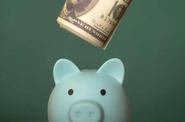 Bankaya para yatıran bir el, uzun vadeli finansal hedeflerin güvence altına alınması için bütçe düzenlemesi ve finansman yönetimini sembolize eder..