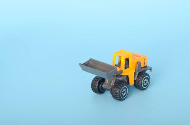 Görüntü sarı oyuncak kepçe yükleyiciyi canlandırıyor yükseltilmiş bir kova ile, canlı mavi bir arka plan üzerine kurulmuş.