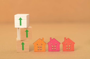 Tahta bloklardaki yukarı doğru oklar yükselen bir konut piyasasını sembolize ederken, küçük evler bireysel mülkleri temsil ediyor..