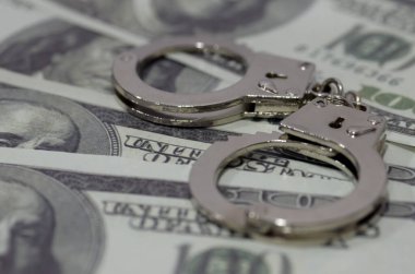 Bir çift kelepçe Amerikan dolarları yatağında yatıyor. Bu birleşme paranın yozlaştırıcı etkisini ya da finansal suçlar potansiyelini ortaya koyuyor..