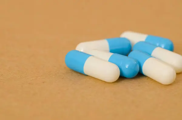 stock image The image depicts a cluster of blue and white capsules, likely antibiotics, highlighting the common use of medication in treating various infections and illnesses.