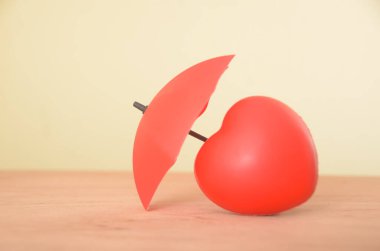 The red heart, partially shielded by a fragmented umbrella, symbolizes the fragility of love, protection shattered in the face of adversity, leaving behind remnants of what once offered comfort. clipart