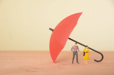 Her ikisi de şemsiye altında korunan bir erkek ve kadın, sigorta poliçelerinin sağladığı korumayı sembolize ediyor