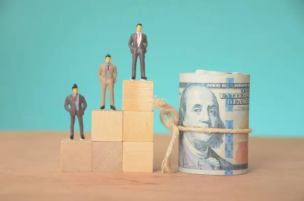 stock image A row of businessmen, each holding a stack of banknotes, symbolizes the pursuit of wealth and financial success in the corporate world.