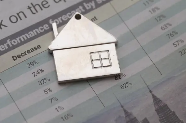 stock image the house figurine and financial data highlights the close relationship between the housing market and broader economic trends.