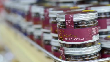 Langkawi, Malezya: 2 Ekim 2024: Süt çikolatasıyla kaplanmış kuru üzüm dolu cam kavanozlar bir rafta sergileniyor.