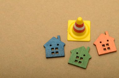 Bir trafik konisi ve birkaç evin görüntüsü, emlak piyasasındaki potansiyel bozulma veya zorluklar kavramını sembolize etmektedir..