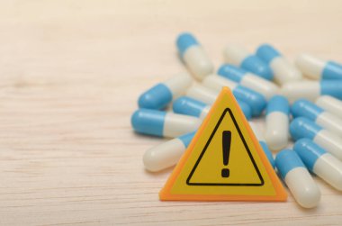 Uyarı üçgeni, dozaj talimatlarına uymanın ve tıbbi tavsiye istemenin önemini vurgular..