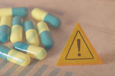 İlaç Kullanımı Tedbiri: İlaç Riskini Belirten Sarı ve Mavi Kapsüller Yakın Uyarı İşareti