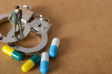 Uyuşturucuya İlişkili Suç ve Hukuki Sonuçları Temsilen Kapsüllerle Kelepçeli Minyatür Figürü