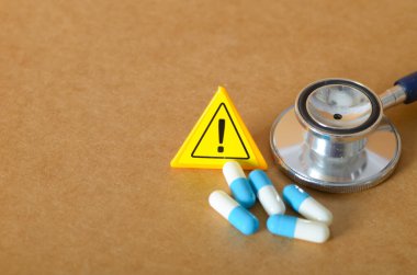 Tıbbi Uyarı: Steteskop, hap ve Dikkat İşareti ile Sağlık Riski Konsepti.