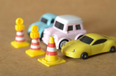 cars in yellow, pink, and blue are arranged with traffic cones in a playful scene representing driving lessons, road safety, and traffic management concepts.