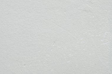 Çeşitli tasarım uygulamaları için çok yönlü ve minimalist bir arkaplan yaratmak için eşit ışıklandırılmış basit, ince desenli, beyaz boyanmış alçı bir duvar..