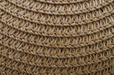 El yapımı bir sepet ya da şapkanın detaylı makro çekimi. Örülmüş doğal liflerin karmaşık desenlerini gösteriyor. Toprak ve kırsal bir arka plan için mükemmel..