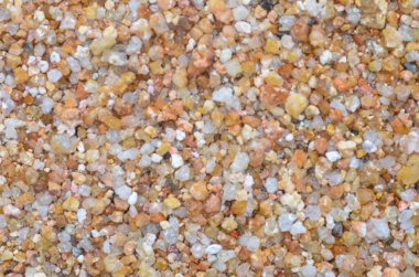 Kaba, çok renkli, turuncu, sarı ve beyaz açısal şekilli kum taneleri doğal bir arkaplan oluşturur..