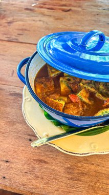 Tahta masadaki mavi tencerede pişmiş yumurta ile Tayland usulü köri..