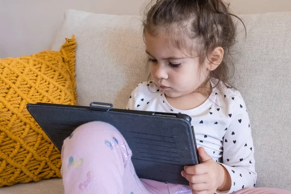 Dijital tablet teknolojisi kullanan tatlı küçük kız kanepenin üzerinde tek başına yatıyor. Evde bilgisayar sörfü yapan küçük bir çocuk var. Çocuklar teknoloji bağımlılığı kavramı. 