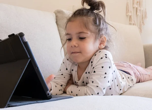 Dijital tablet teknolojisi kullanan tatlı küçük kız kanepenin üzerinde tek başına yatıyor. Evde bilgisayar sörfü yapan küçük bir çocuk var. Çocuklar teknoloji bağımlılığı kavramı. 