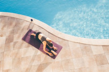 Akşamları havuz başında yoga yapan genç bir kadın. Yüksek kalite fotoğraf