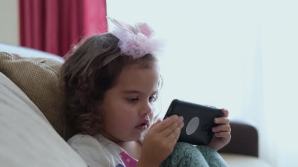 Cute Little Kid Girl Using Mobile Phone Sitting Sofa Alone — Stockvideo
