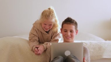 Teenager boy and girl using laptop computer, having fun and fool around at home. 4k footage