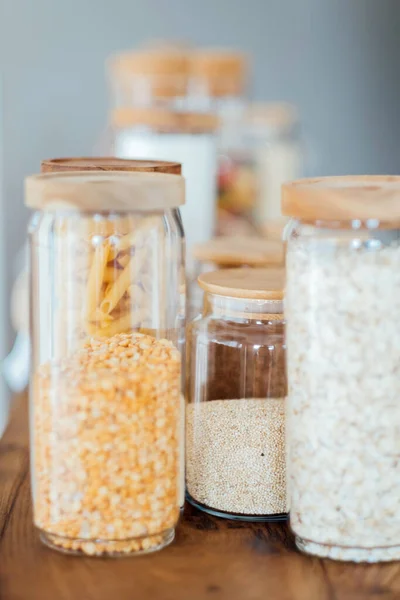 Zero waste concept. Textile eco-bags, glass jars with grocery on a wooden table in the kitchen. Eco-friendly reuse concept. Selective focus.