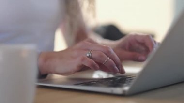 Ev ofisinde çalışan bir kadın. Eller bilgisayar klavyesinde, yakın plan. Yüzük dekorasyonlu güzel kadın parmakları hızla bir metin yazıyor..