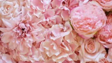 Floral background texture for ceremony or photo shoot. Artificial flowers in pastel colors on the wall. Selective focus.