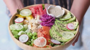 Top view in rainbow colored fruit and vegetable lunch bowl. Woman hands holding salad. Healthy eating. 4k footage