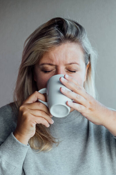 Портрет женщины, пьющей кофе с закрытыми глазами. Наслаждайтесь напитком