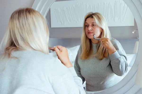 Blonde Frau Größe Lässiger Kleidung Mit Gesichtsmassagegerät Spiegel Tägliche Schönheitsbehandlungen — Stockfoto