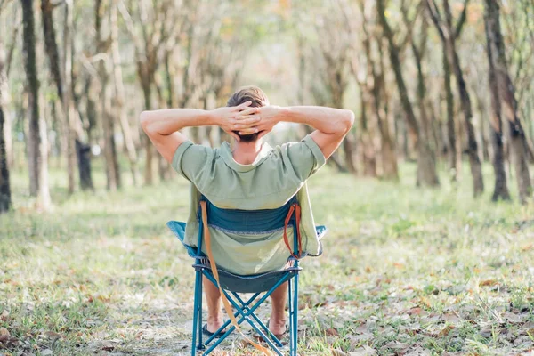 stock image Back view on young man enjoing sunlight in green summer park. Relaxing on nature.