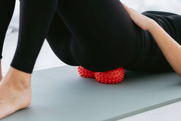 Woman lying on small balls to eliminate back pain, massage stiff muscles and lower back pain, perform exercises to relieve pain in the sacrum and spine. Relaxation and stretching of muscles