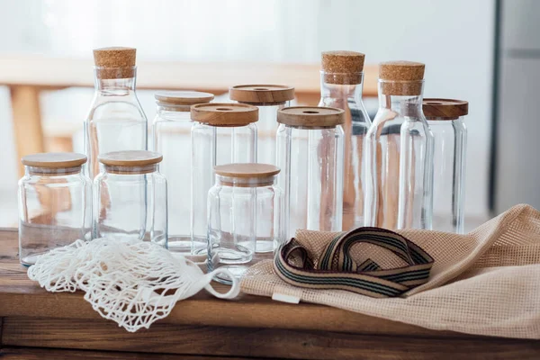 Zero waste concept. Textile eco-bags, empty glass jars on a wooden table in the kitchen. Eco-friendly reuse concept. Selective focus.