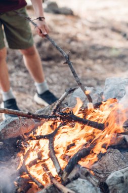 Şenlik ateşinde çubukta marşmelov kızartan çocuk. Çocuk kamp ateşinde eğleniyor ve tatlı pişiriyor. Kamp yapan çocuklar için tedavi.