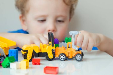 Boy plays colorful multi-colored cubes and cars on the table. Early development and learning. . High quality photo