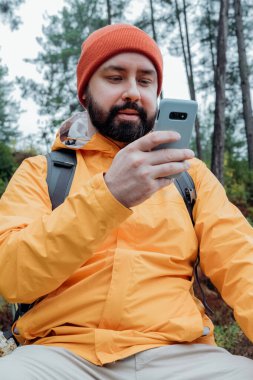 Şapkalı sakallı adam cep telefonu kullanıyor. Adam cep telefonuna bakıyor ve gülümsüyor.. 