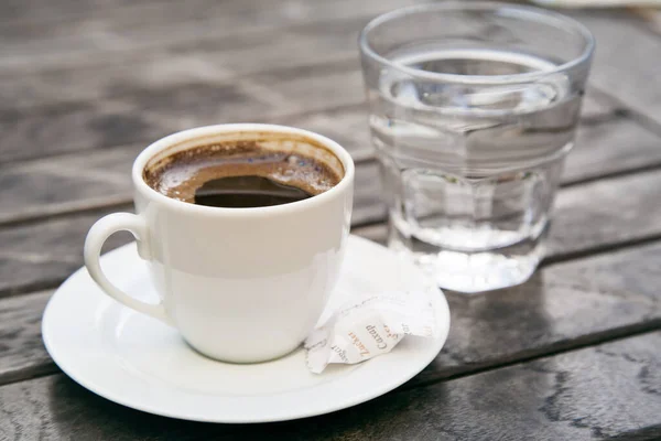 Mała Filiżanka Mocnego Kawy Espresso Szklanką Czystej Wody Drewnianym Stole — Zdjęcie stockowe