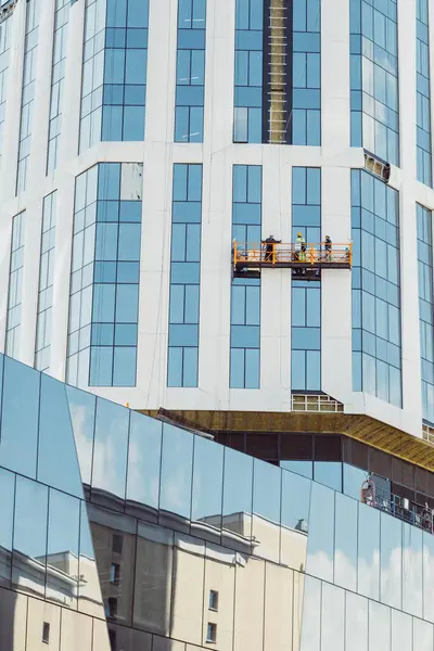 Professional high rise window cleaning service workers. Workers using specialized equipment to access and clean windows of skyscraper as preventative maintenance and repair measure.