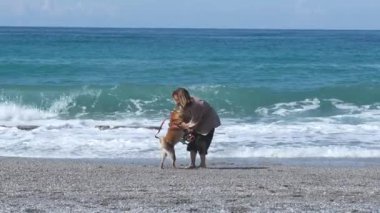 Kadın ve köpek arkadaşı Shiba bu güzel kumsalda çok iyi vakit geçiriyorlar..