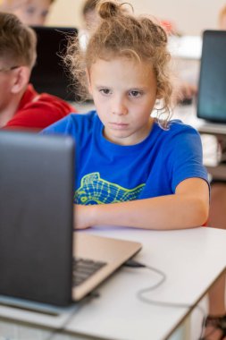 İlkokulda bilgisayar sınıfında. Liseli çocuk dizüstü bilgisayarla çalışıyor. Okul çocukları modern teknoloji eğitimi alıyorlar.