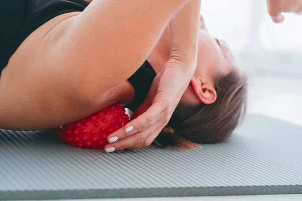 Woman lying on small balls to eliminate back pain, massage stiff muscles and thoracic back pain, perform exercises to relieve pain in spine. Relaxation and stretching of muscles