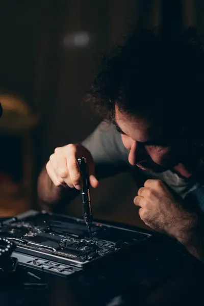 Man upgrading or repairing the laptop computer. Dark photo