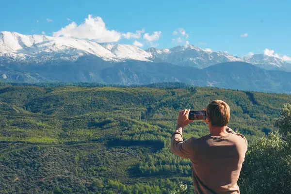 Man tacking photos of epic landscape view while traveling alone
